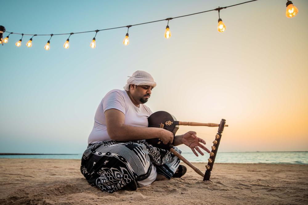 A man plays a Simsimiyya on the beach.